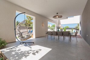 Eine großzügige Terrasse mit einer Hängematte, einem Essbereich mit Stühlen und einer Aussicht ins Freie.