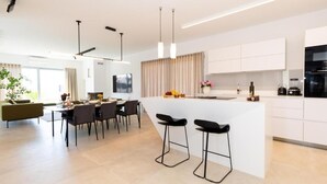 Una cucina moderna con isola centrale, sgabelli da bar e zona pranzo con tavolo e sedie.