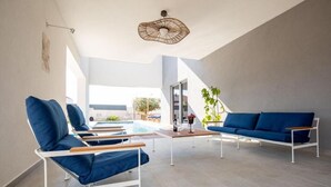 Zona relax esterna moderna con piscina, sedute blu e lampadario sospeso.