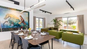 Un'area pranzo moderna con un tavolo apparecchiato per sei persone, un divano verde e un grande quadro appeso al muro.