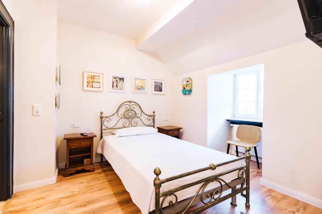 A bedroom with a bed, bedside tables, a chair, and artwork on the wall.