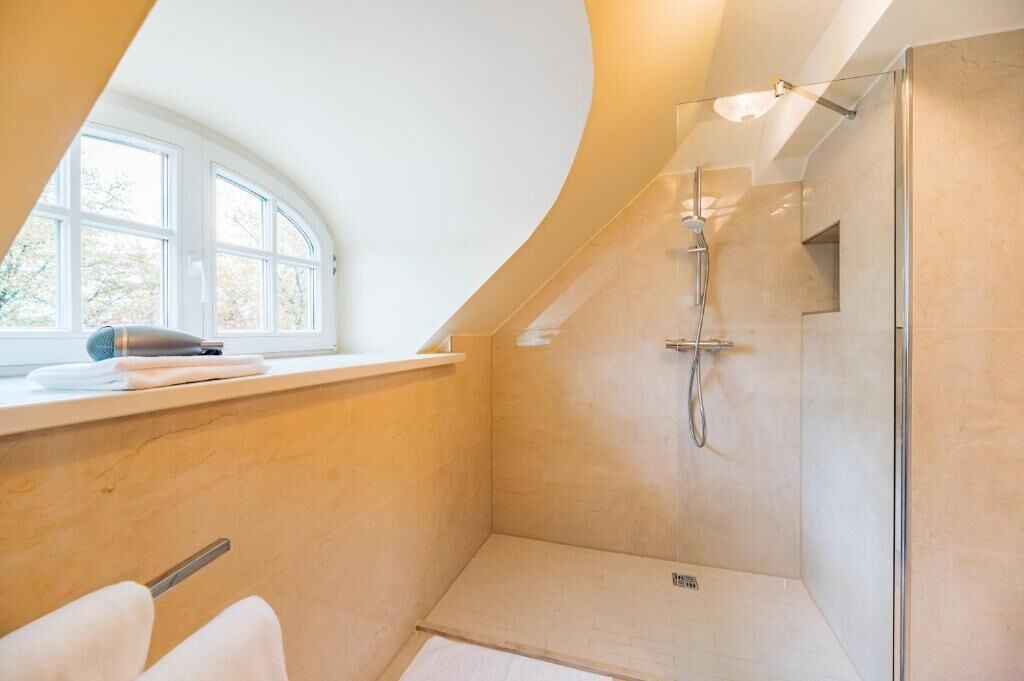 A modern bathroom with a shower, a window, and a towel rack.