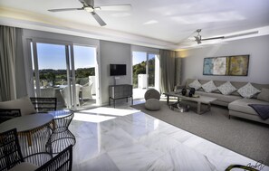 A spacious living room with a large sliding glass door leading to a balcony, a ceiling fan, a flat-screen TV, and a sofa with patterned cushions. - Tranquil Sea View Villa for 8 (Marbella)