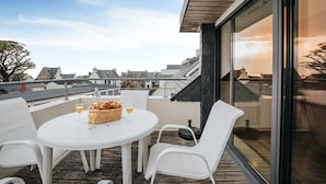 A rooftop terrace with a table set for two, a wicker basket, and a glass of orange juice. - Duplex Apartment With Terrace and sea View (Le Conquet)