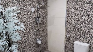 Ett badrum med väggar beklädda med mosaik, en dusch och en toalett.