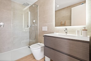 A modern bathroom with a glass-enclosed shower, a white toilet, and a vanity with a mirror. - Modern 3-pax Apartment With Solarium (Casares)