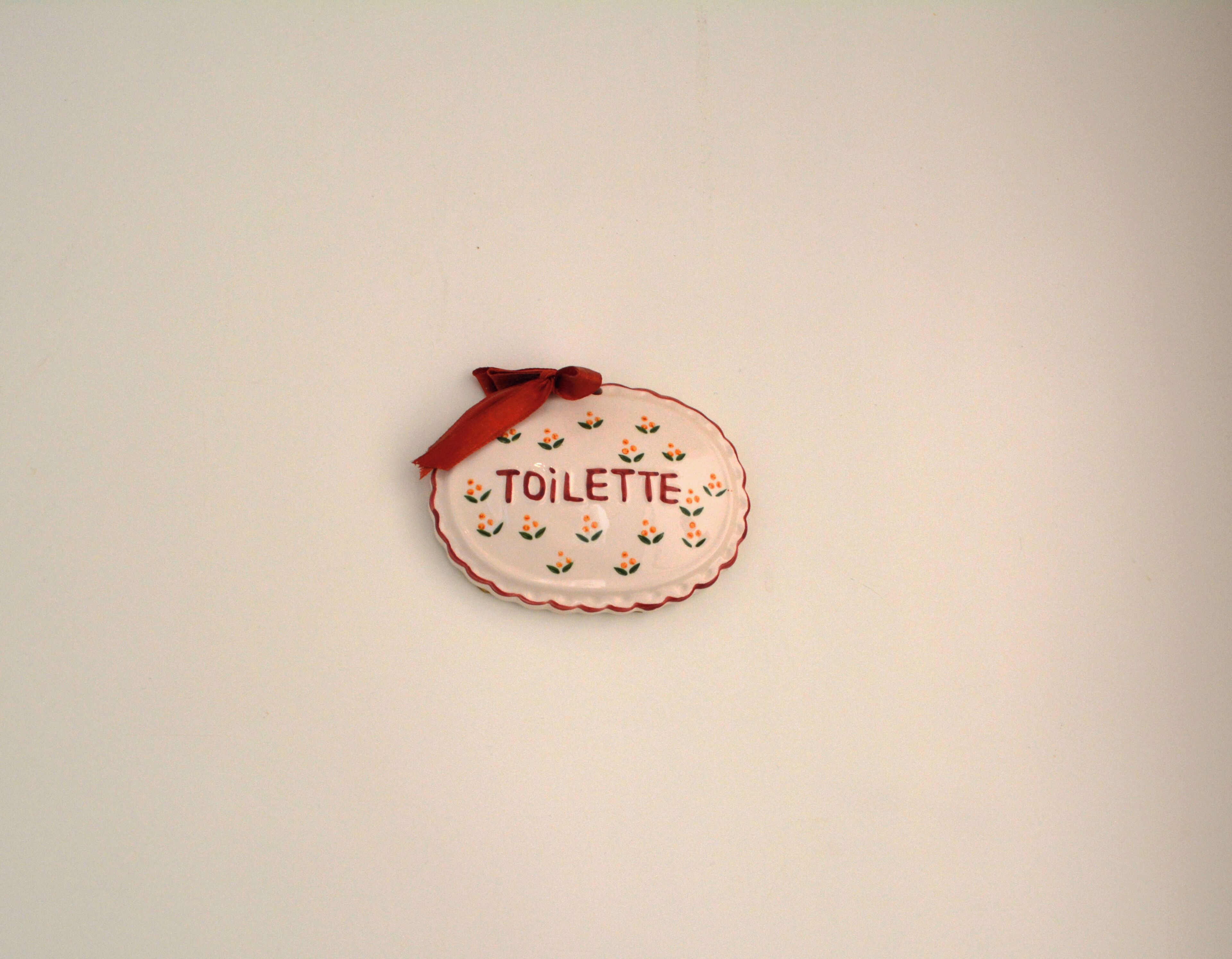 A white plate with the word "TOILETTE" and floral patterns.