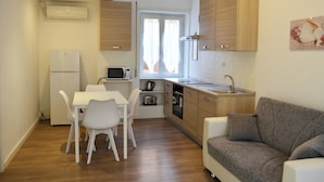 A compact kitchen with a dining area, a built-in oven, and a grey sofa. - Francy's House, just minutes from the Vatican (Roma)