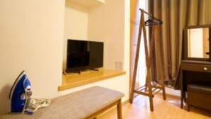 Una stanza modesta con una panca di legno, una televisione su un mobile e uno specchio appeso al muro.