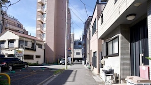 Una stretta via cittadina fiancheggiata da edifici, con un'auto parcheggiata e una bicicletta.