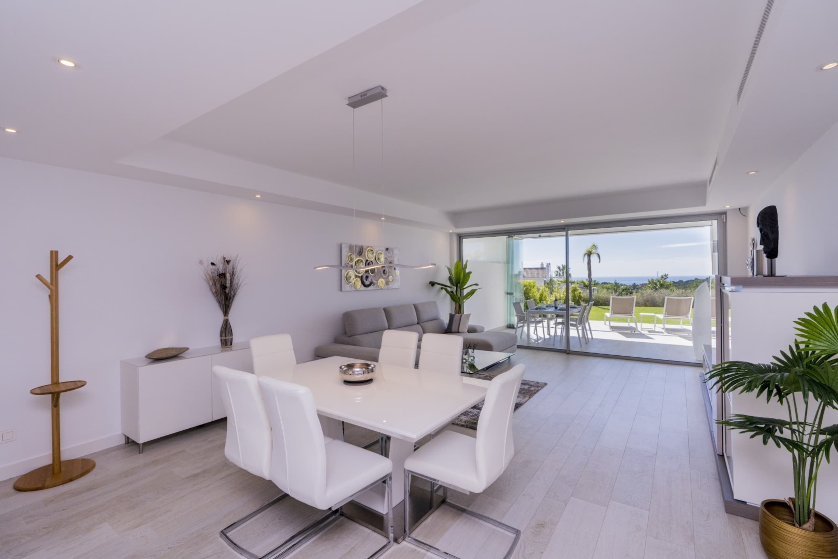 Un interior moderno con comedor, sofá y vistas al exterior.