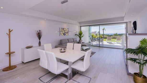 Un interior moderno con comedor, sofá y vistas al exterior.