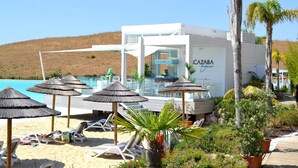 Un hotel frente a la playa con piscina, tumbonas y sombrillas.