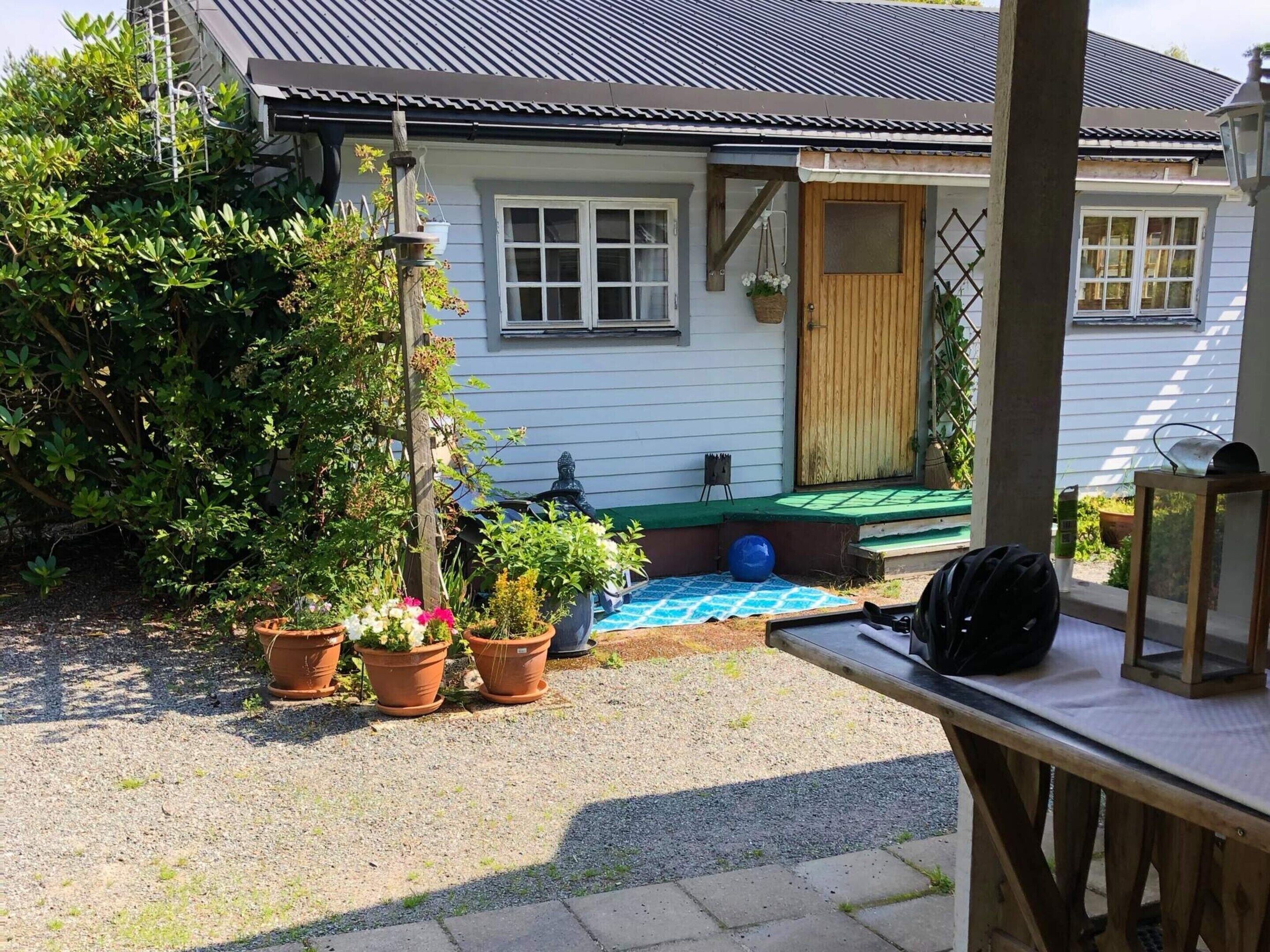 A house with a porch, potted plants, and a blue mat.