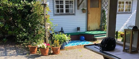 A house with a porch, potted plants, and a blue mat.