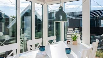Un comedor moderno con una mesa blanca, sillas e iluminación colgante.