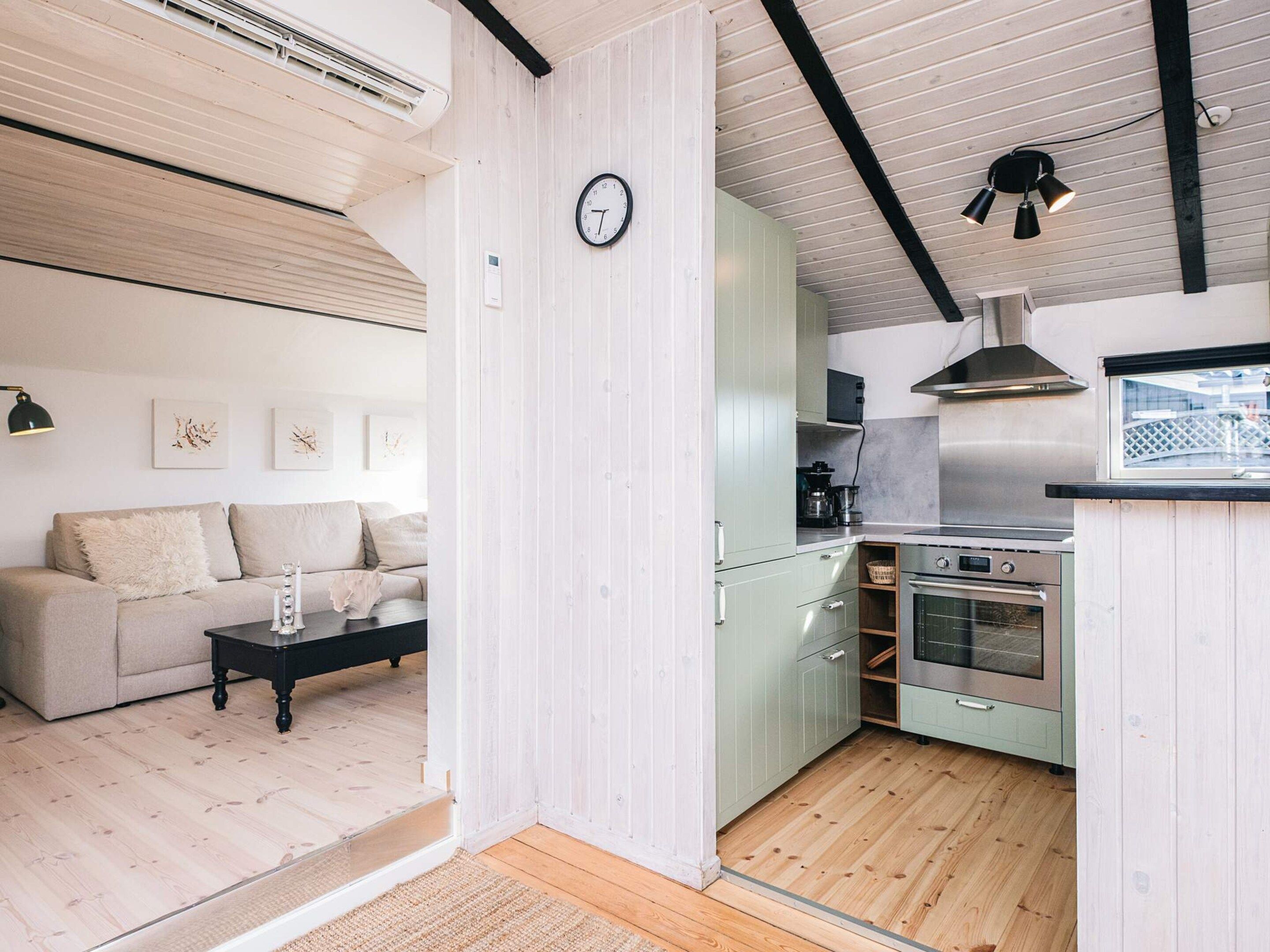 A modern kitchen with a built-in oven and a dining area with a sofa and a coffee table.