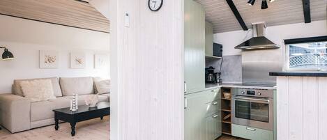 A modern kitchen with a built-in oven and a dining area with a sofa and a coffee table.