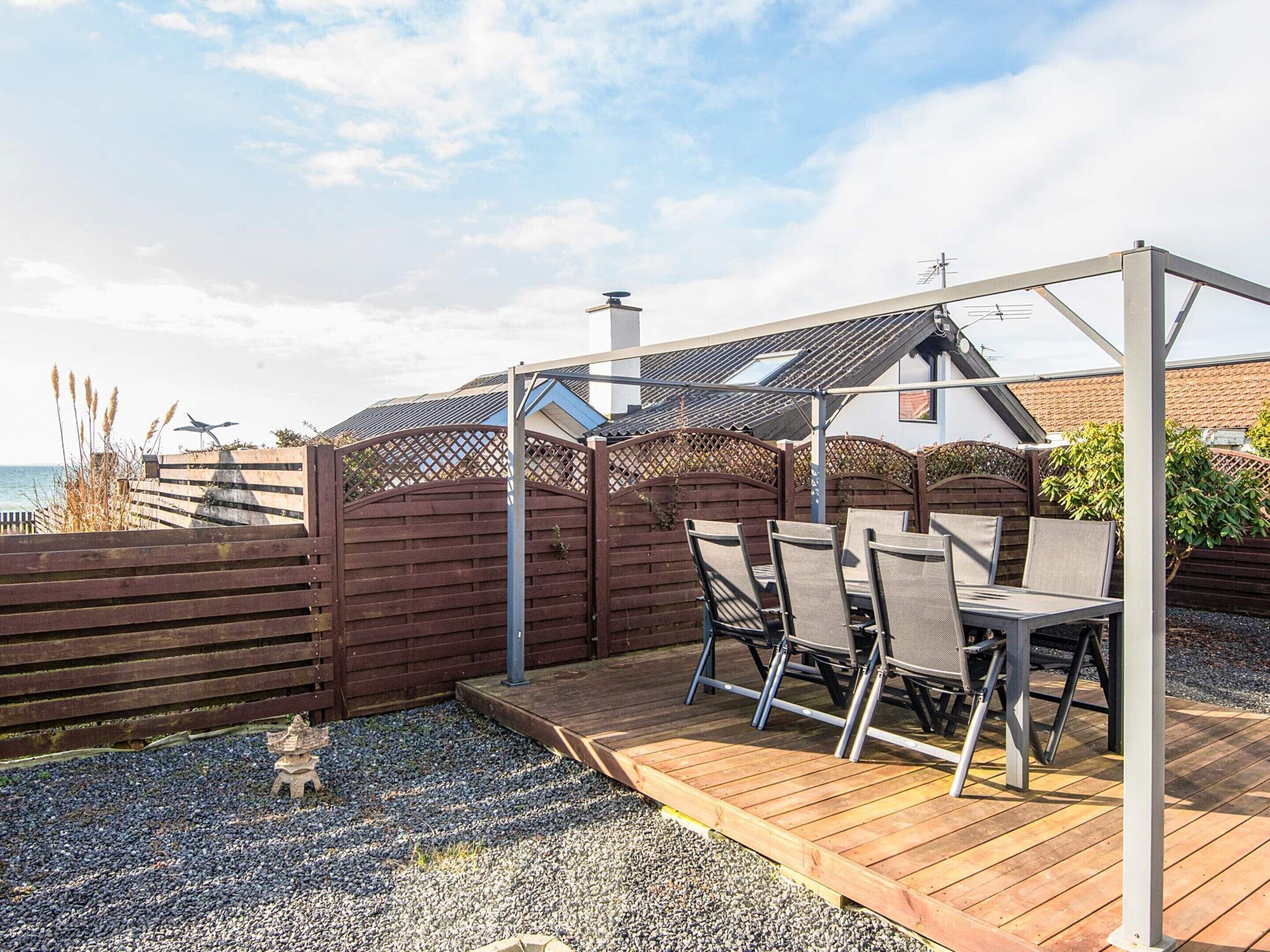 En patio med et bord og stole, en pergola og havudsigt.
