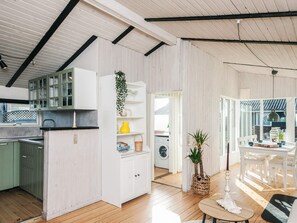 A modern kitchen with white cabinetry, a wooden floor, and a view into the dining area.
