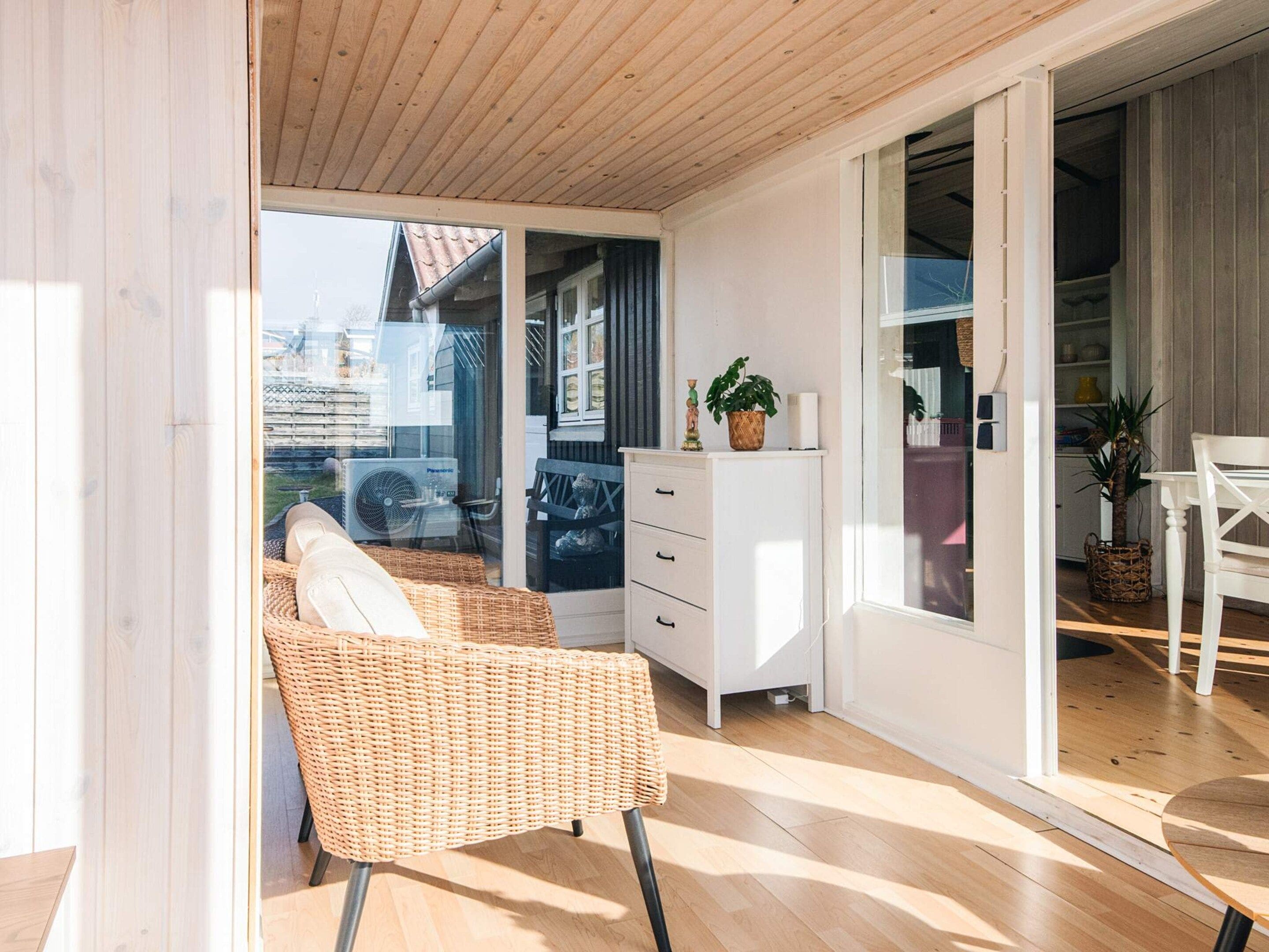 A bright room with a wicker chair, a white cabinet, and a sliding glass door leading to an outdoor area.