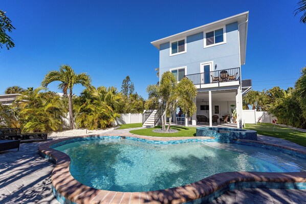 A two-story house with a swimming pool, surrounded by palm trees and a well-maintained lawn. - Dolphins Delight: Rooftop deck, large heated pool, hot tub (Anna Maria)