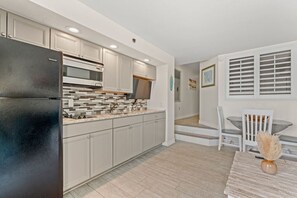 Eine moderne Küche mit Kühlschrank, Mikrowelle und Herd, die in einen Essbereich mit Tisch und Stühlen übergeht.