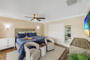 A bedroom with a bed, nightstands, a ceiling fan, a mirror, and a view of the outside. - Waterfront Home | Pool, Hot Tub, Kayak, & Billiards (Marco Island)