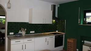 A kitchen with white cabinets, a green tiled backsplash, a wooden countertop, and a black oven. - Altstrimmig Shine (Altstrimmig)