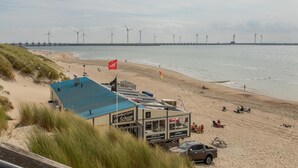 A beachside building with a blue roof, a flag, and a sign indicating it is a restaurant. - 2-bedroom Family Retreat Near Dunes (Burgh-Haamstede)