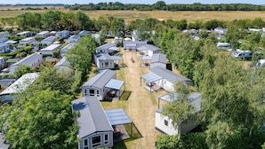 A mobile home park with multiple units, some with attached porches, surrounded by trees and open fields. - 2-bedroom Family Retreat Near Dunes (Burgh-Haamstede)