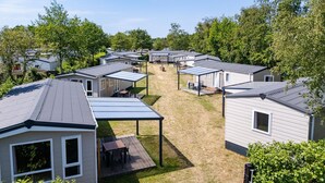 A row of mobile homes with attached patios, surrounded by trees. - 2-bedroom Family Retreat Near Dunes (Burgh-Haamstede)