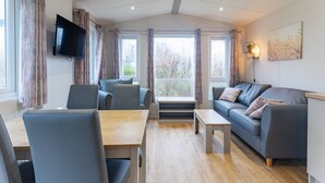 A modern living room with a sofa, chairs, a table, and a TV. - 2-bedroom Family Retreat Near Dunes (Burgh-Haamstede)