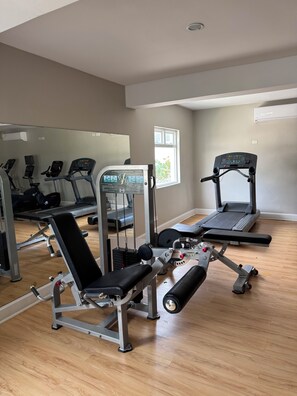 A gym with exercise equipment including treadmills, a bench press, and a weight machine.