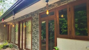 A covered outdoor area with wooden doors and windows, potted plants, and a sink.