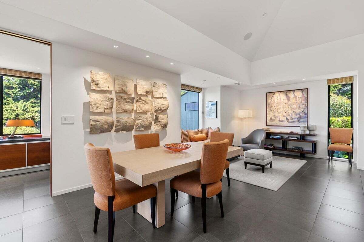 Un espace repas moderne avec une grande table, des chaises et un mur décoratif.