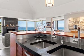 A modern kitchen with a large island, stainless steel appliances, and a view of the ocean. - Hedgerow Haven | Premium Oceanfront with Hot Tub (The Sea Ranch)