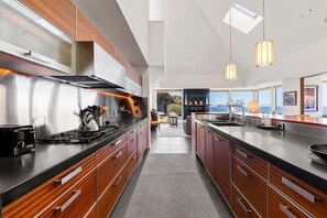 A modern kitchen with a central island, stainless steel appliances, and wooden cabinetry. - Hedgerow Haven | Premium Oceanfront with Hot Tub (The Sea Ranch)