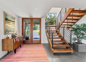 A modern interior with a wooden staircase, a dining area with a patterned rug, and a large painting on the wall. - Premium 1 acre oceanfront property (The Sea Ranch)