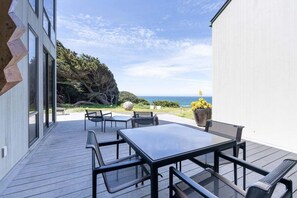 Eine Terrassenanlage im Freien mit Tisch und Stühlen, mit Blick auf ein Gewässer und Grünflächen.