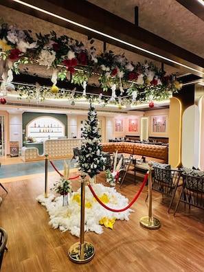 A lobby with a Christmas tree, red velvet ropes, and a bar area with a leather couch.