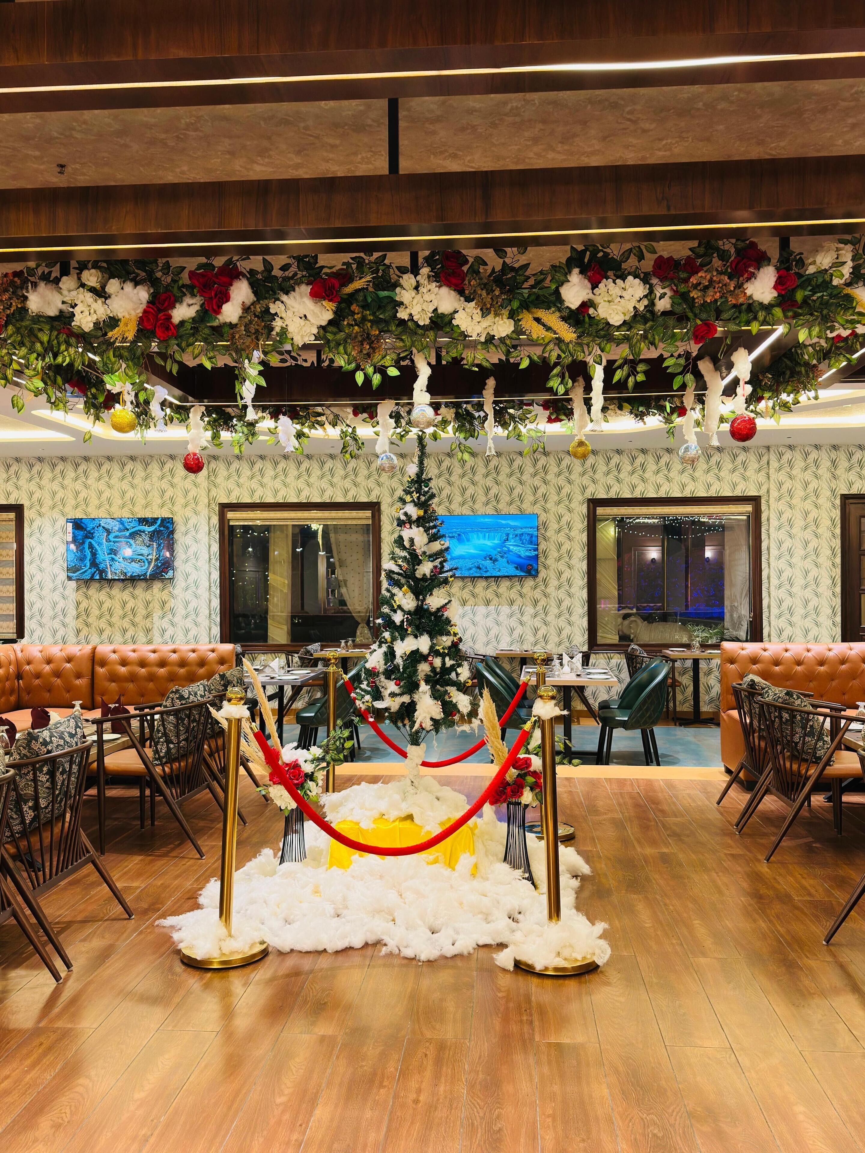 A lobby with a Christmas tree, leather sofas, and a TV screen.