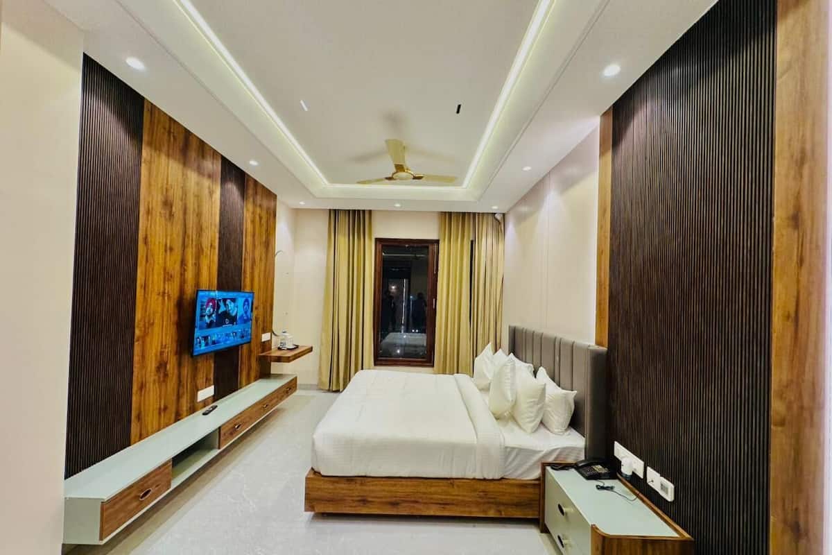 Un dormitorio moderno con una cama grande, un televisor en la pared y un ventilador de techo.