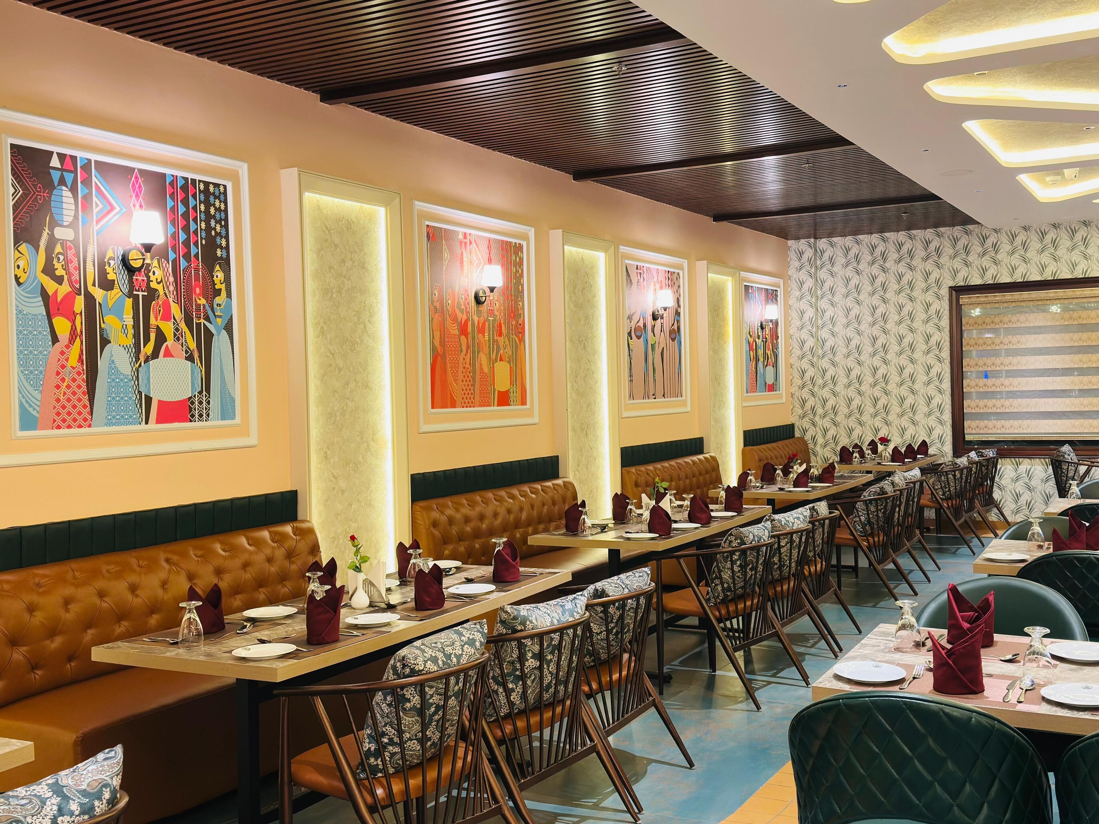 A restaurant with long communal tables, cushioned booths, and decorative wall art.