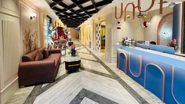 Una hall d'albergo con una reception, un divano, un tavolino da caffè e un'elegante composizione floreale.