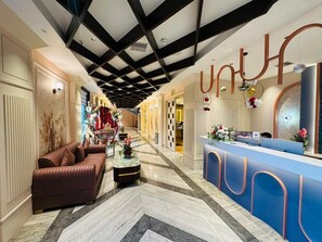 Eine Hotelhalle mit Empfangstresen, einer Couch, einem Couchtisch und einer dekorativen Blumenkomposition.