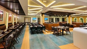 Un'ampia sala ristorante con lunghe tavolate, comode cabine imbottite e un moderno design del soffitto.