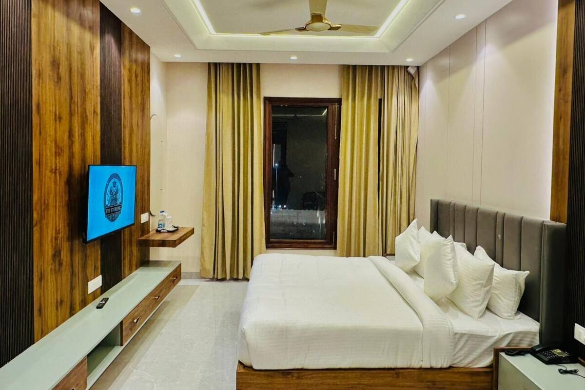Una habitación de hotel moderna con una cama grande, un televisor en la pared y una ventana con cortinas.