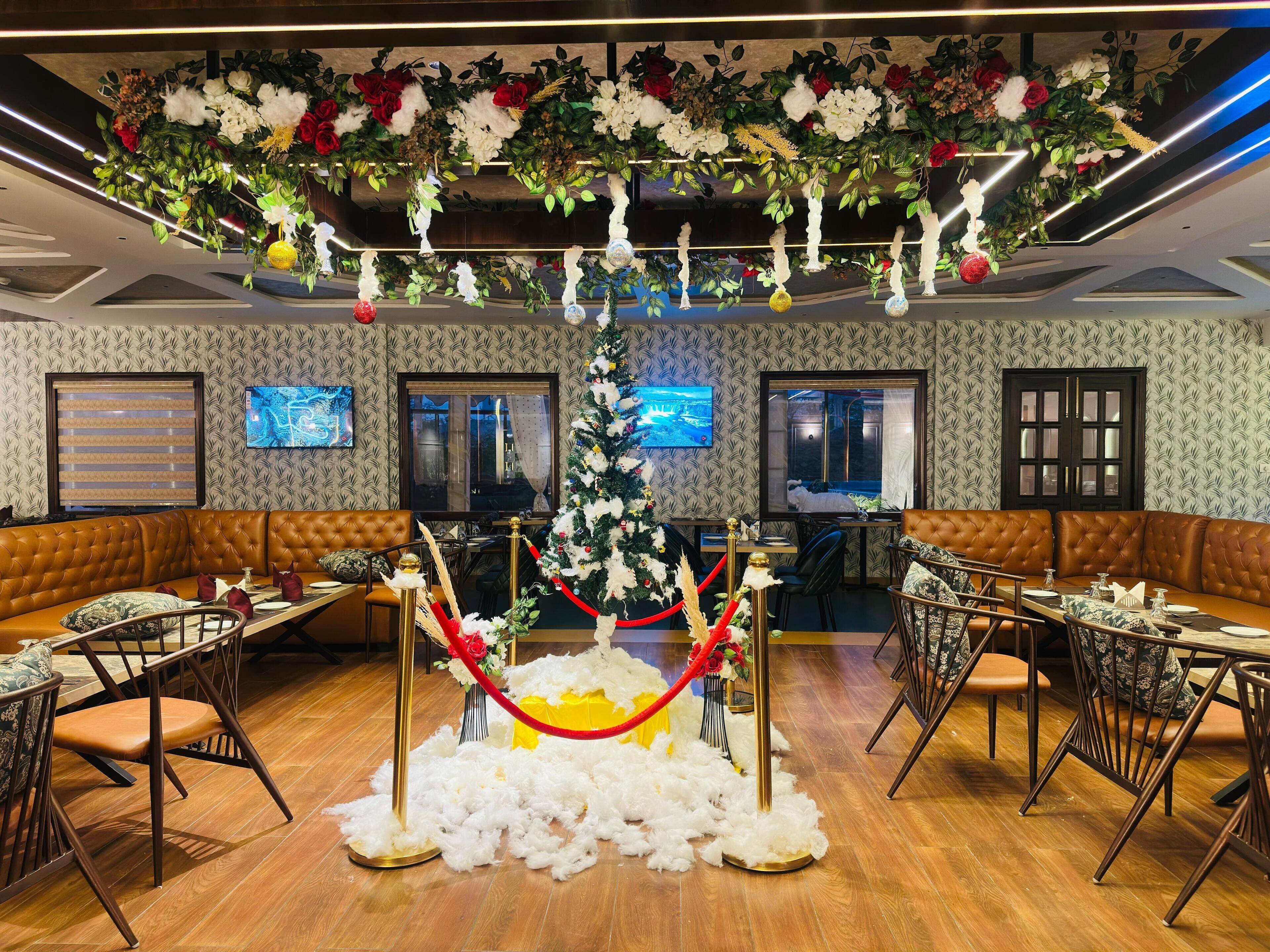 A restaurant with a Christmas tree, red ropes, and a white fluffy carpet on the floor.