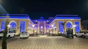 Un hotel con ingresso centrale, diversi posti auto e una strada di accesso pavimentata.